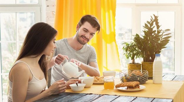 Casal feliz passando a manhã juntos. Homem casual e mulher apaixonada tomando café da manhã, copie o espaço