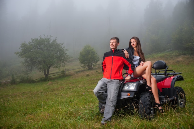 Foto casal feliz perto de quadriciclo atv na natureza nevoenta