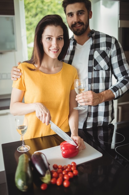 Foto casal feliz picar legumes na cozinha