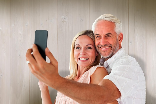 Casal feliz posando para uma selfie contra pranchas de madeira