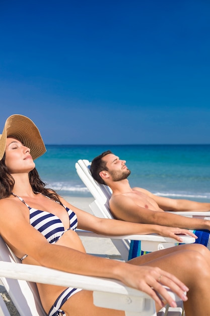 Casal Feliz relaxando na espreguiçadeira na praia