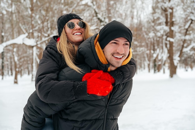 Casal feliz se abraçando e sorrindo ao ar livre em um parque nevado