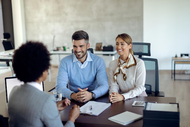 Foto casal feliz se comunicando com consultor financeiro em uma reunião no escritório