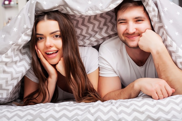 Casal feliz se divertindo na cama. Casal jovem sensual íntima no quarto, amando um ao outro