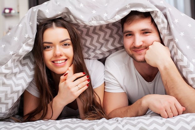 Casal feliz se divertindo na cama. Casal jovem sensual íntima no quarto, amando um ao outro