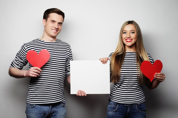 Casal feliz segurando corações em branco e vermelhos brancos.