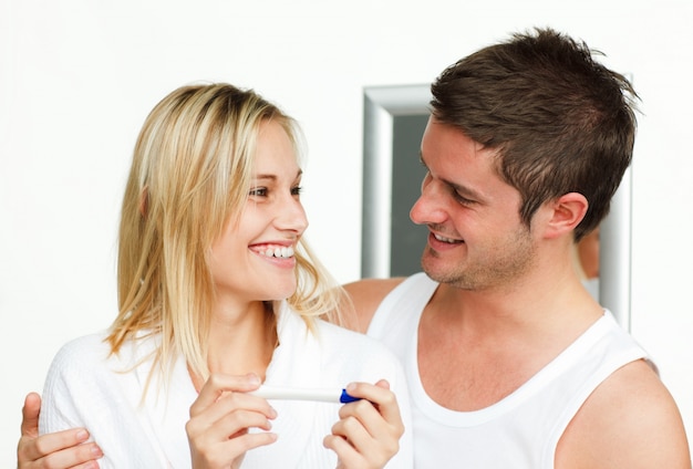 Casal feliz segurando um teste de gravidez olhando um ao outro