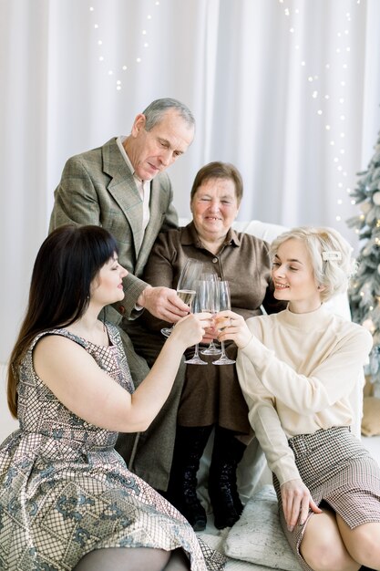 Casal feliz sênior bebendo taças de champanhe com suas duas lindas netas