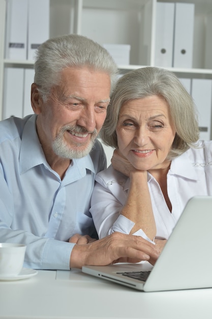 Casal feliz sênior com laptop no escritório