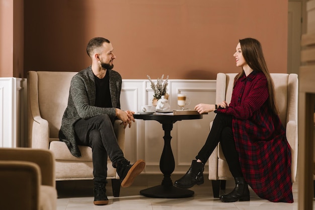 Casal feliz sentado à mesa com café no lobby do hotel