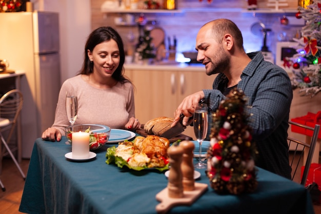 Casal feliz sentado à mesa de jantar na cozinha decorada de natal