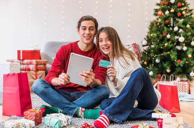 Casal feliz sentado com tablet no chão