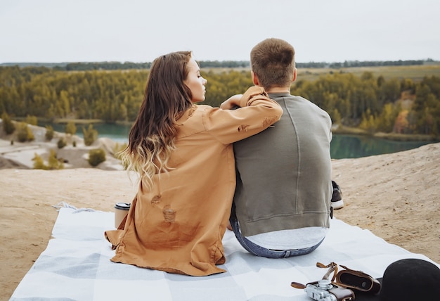 Casal feliz sentado em uma manta e apreciando a vista da natureza.