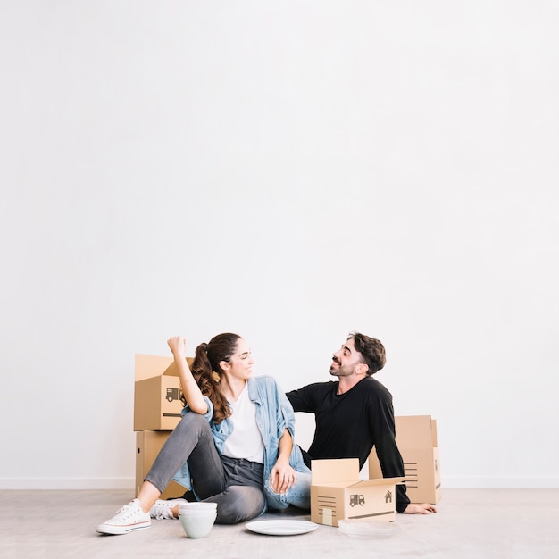 Casal feliz sentado na frente de caixas móveis