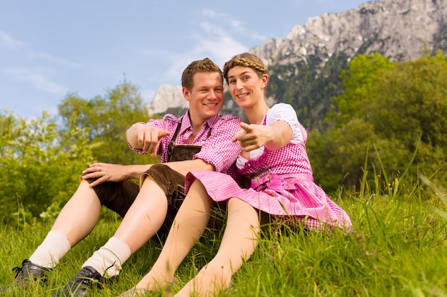 Casal feliz sentado no Prado alpino