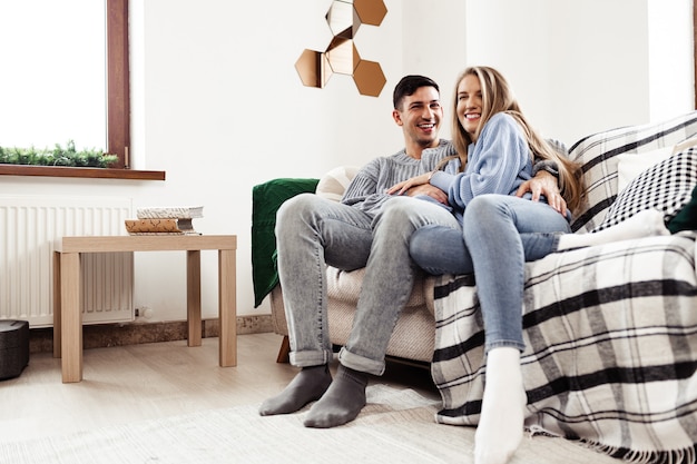 Casal feliz sentado no sofá da sala