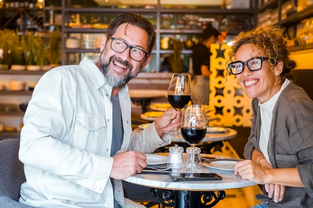 Casal feliz sorrindo e conversando em um restaurante bebendo vinho tinto Casal almoçando no café bar Conceito de estilo de vida com homem e uma mulher saindo no dia de fim de semana