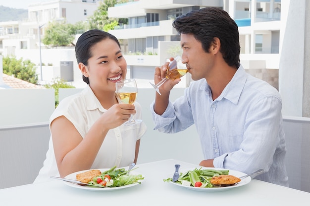 Casal feliz tendo uma refeição juntamente com vinho branco