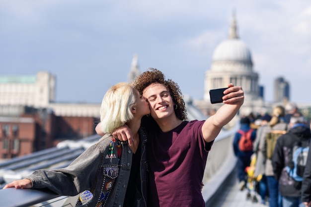 Foto casal feliz tirando uma foto de selfie na ponte do milênio de londres