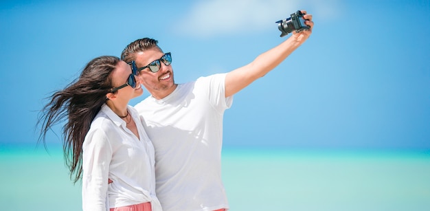 Casal feliz, tirando uma foto de selfie na praia branca. Dois adultos curtindo suas férias na praia exótica tropical