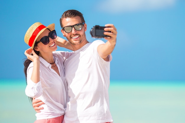 Casal feliz, tirando uma foto na praia branca de férias de lua de mel