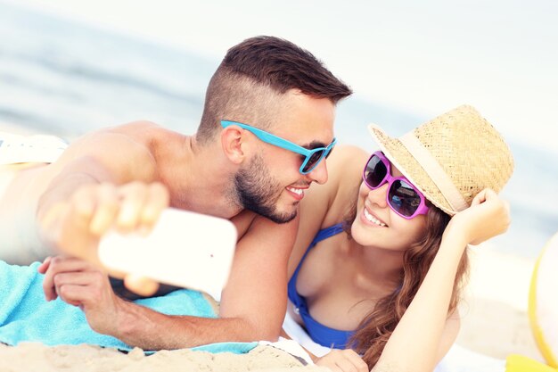 casal feliz tirando uma selfie na praia