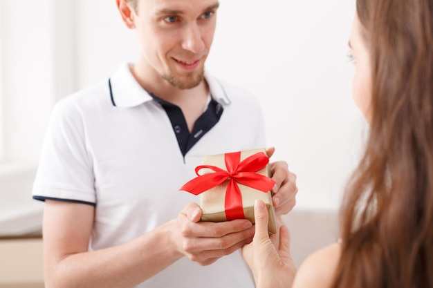 Casal feliz trocando presentes. Homem sorridente segurando uma caixa de presente e olhando para a namorada, copie o espaço