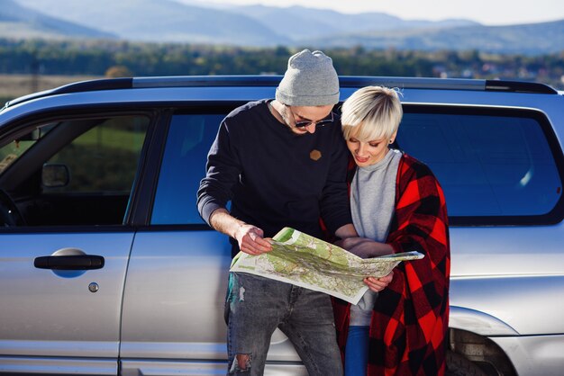Casal feliz turista com papel mapa perto de carro alugado.