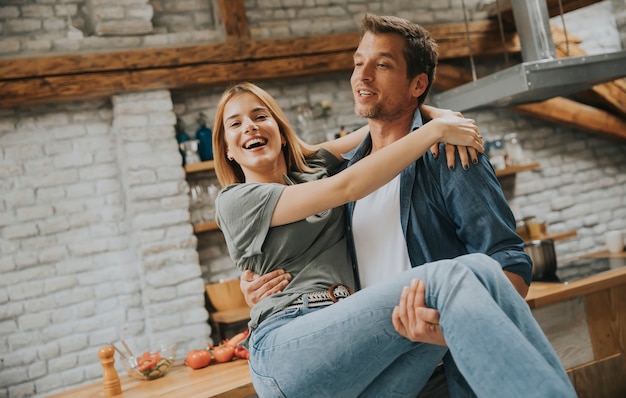 Casal feliz um ao outro na cozinha moderna enquanto homem segurando a mulher nas mãos