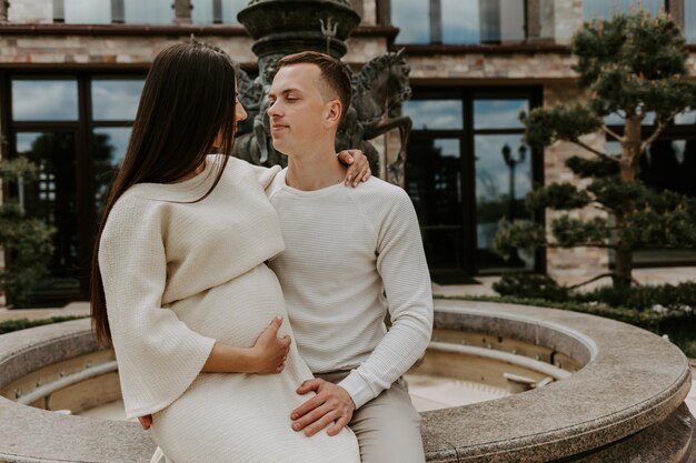 Casal feliz, uma jovem linda esposa grávida em um vestido longo e marido caminhando juntos em um dia ensolarado de verão Homem e mulher apaixonados