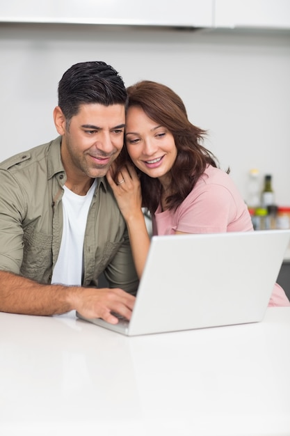 Casal feliz usando laptop na cozinha