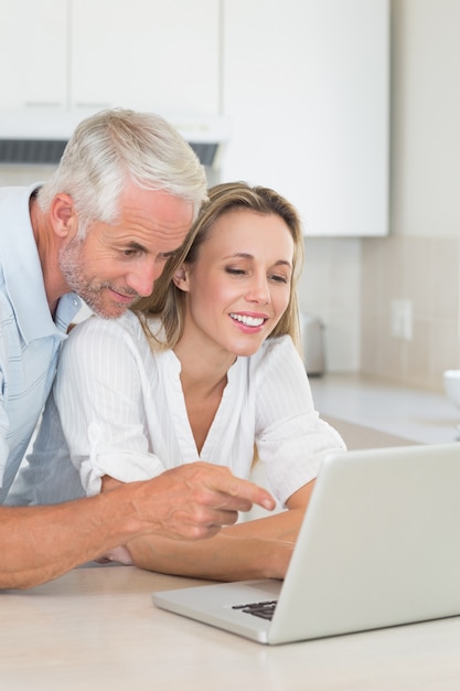 Casal feliz usando o laptop juntos no balcão