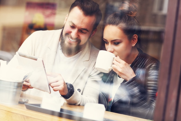 casal feliz usando tablet em restaurante