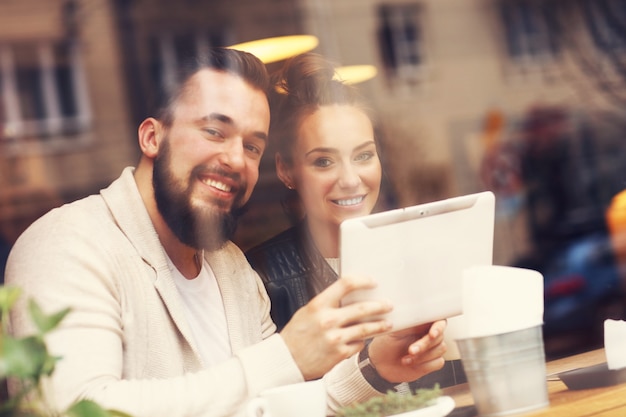 casal feliz usando tablet em restaurante