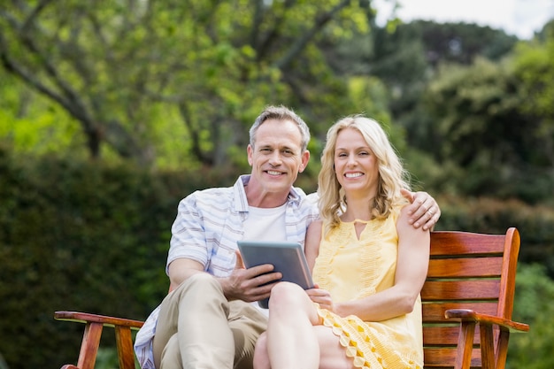 Casal feliz usando tablet em um banco fora