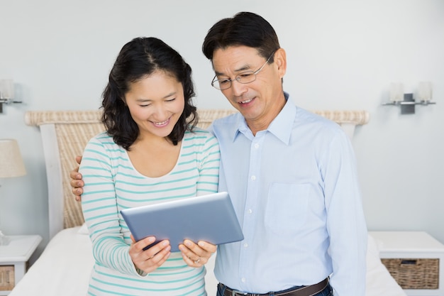 Casal feliz usando tablet no quarto