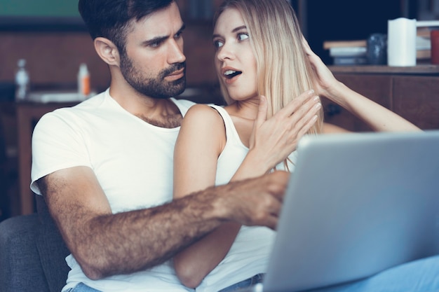 Casal feliz usando um laptop no sofá.