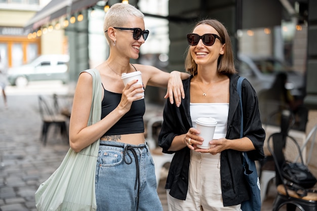 Casal feminino elegante dançando junto com uma xícara de café ao ar livre