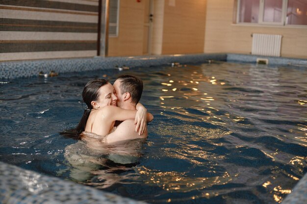 Casal fofo abraçando enquanto nadava juntos na piscina interna