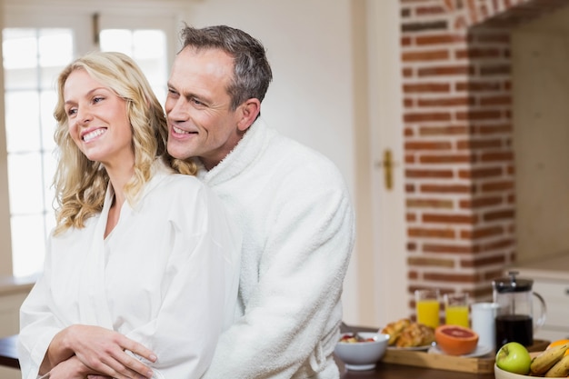 Casal fofo carinhos em roupões na cozinha