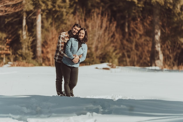 Casal fofo dançando na floresta de inverno de mãos dadas e rindo História de amor Foco seletivo