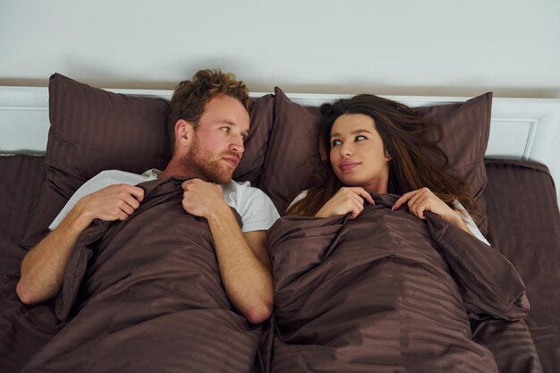 Foto casal fofo deitado na cama juntos interior e design do belo quarto moderno durante o dia