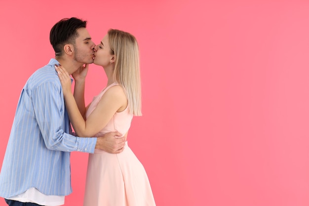 Casal fofo e feliz se beijando no fundo rosa