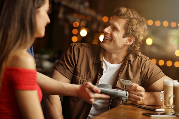 Casal fofo em um café pagando com cartão de crédito