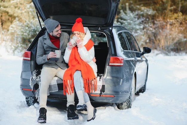 Casal fofo fazendo piquenique na floresta de inverno, bebendo chá do chá, xícara para viagem, piquenique, história de amor, data, no carro