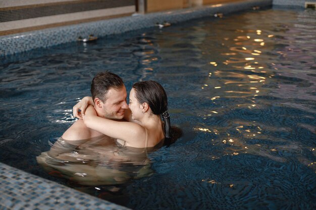 Casal fofo nadando juntos na piscina interna