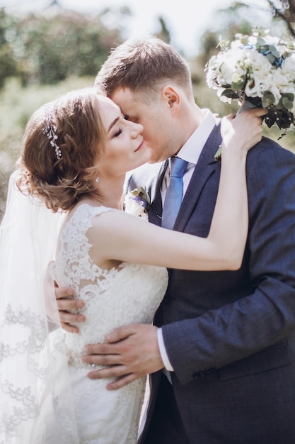 Casal fofo recém-casado se beija em um parque feliz noiva e noivo se abraçando ao ar livre no jardim de verão mulher bonita e homem bonito momento romântico