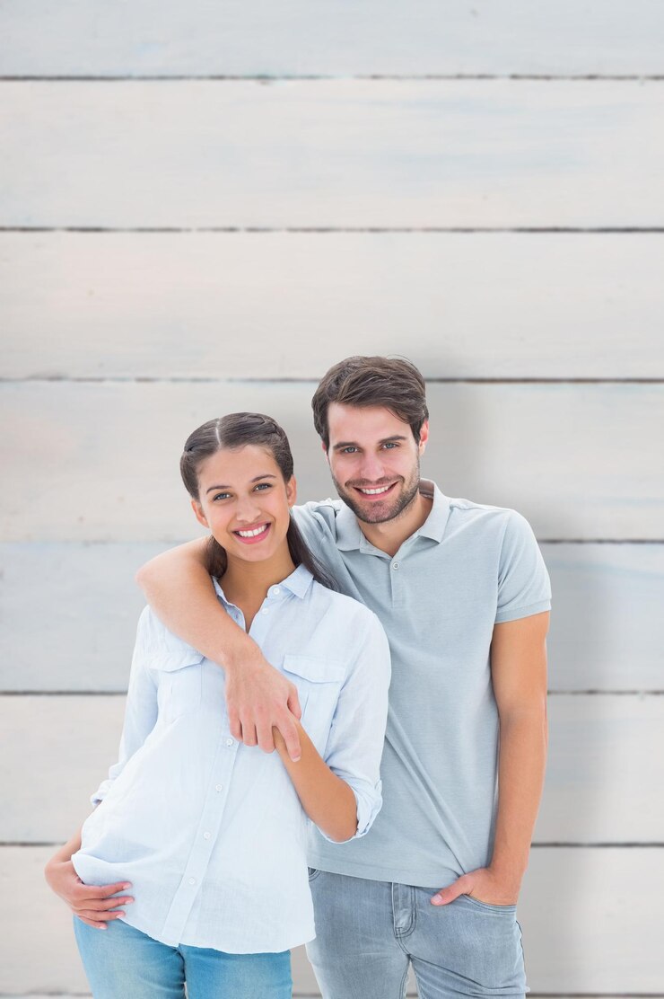 Foto casal fofo sorrindo para a câmera contra pranchas de madeira
