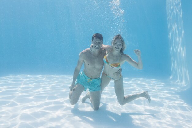 Casal fofo sorrindo para a câmera debaixo d&#39;água na piscina