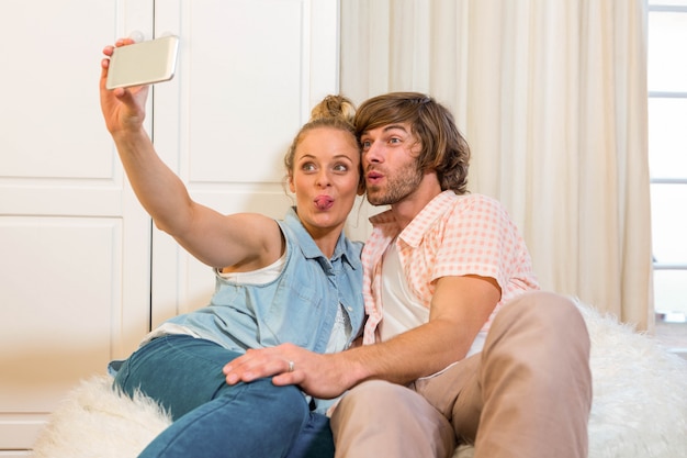 Casal fofo tomando uma selfie com smartphone na sala de estar